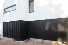 Construction d'une habitation - façade - crépi/panneau noir  - porte intégrée